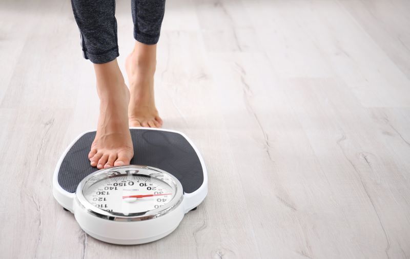 Person weighing themselves after weight loss treatment